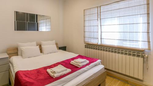 1 dormitorio con 1 cama con 2 toallas en Apartment Central Square, en Belgrado