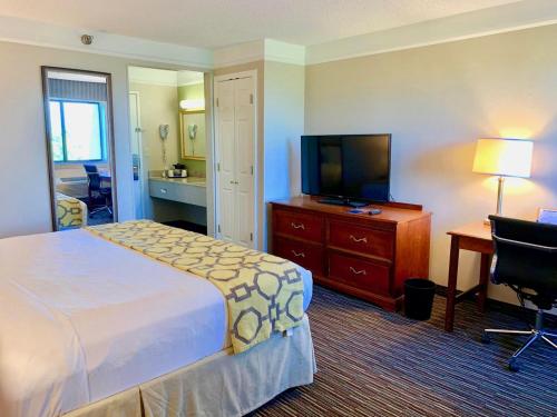 a hotel room with a bed and a desk and a television at Baymont by Wyndham Texarkana in Texarkana