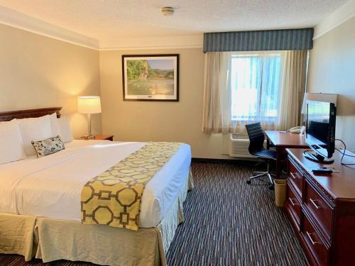a hotel room with a bed and a desk and a television at Baymont by Wyndham Texarkana in Texarkana