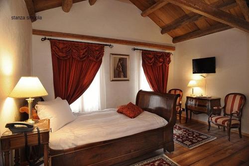 a bedroom with a bed with red curtains and a desk at Park Hotel Villa Carpenada in Belluno