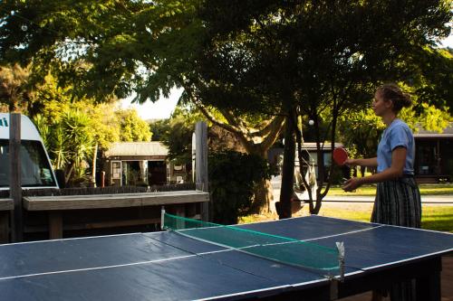 a girl playing ping pong on a ping pong table at The Barn Cabins & Camp in Marahau