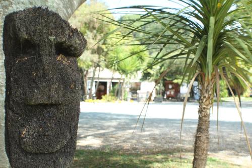 a statue of a head next to a palm tree at The Barn Cabins & Camp in Marahau
