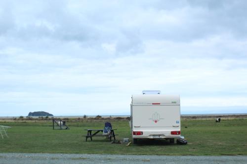 a white caravan parked in a field with a picnic table at The Barn Cabins & Camp in Marahau