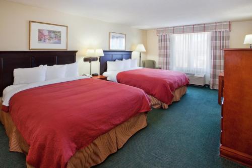 a hotel room with two beds with red sheets at Country Inn & Suites by Radisson, Hiram, GA in Hiram