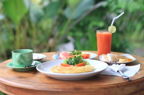 a table with plates of food and a cup of juice at Esty House in Ubud