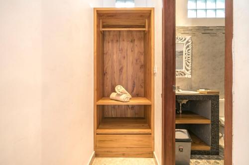 a bathroom with a wooden closet with a sink at Esty House in Ubud