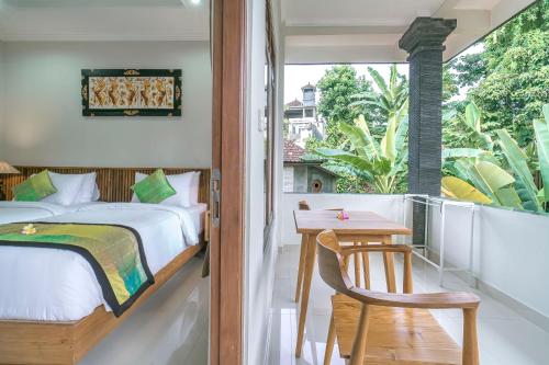 a bedroom with a bed and a table and a window at Esty House in Ubud