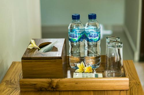 two bottles of water and glasses on a wooden table at Esty House in Ubud