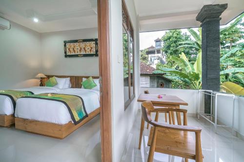 a bedroom with a bed and a table and a window at Esty House in Ubud