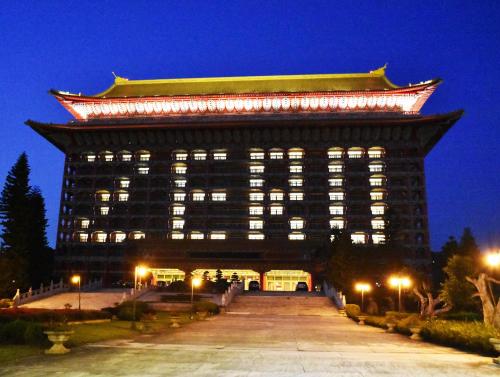 a large building with lights on it at night at The Grand Hotel in Taipei