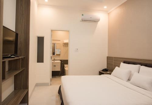 a bedroom with a white bed and a television at Amora Hotel & Apartment in Vung Tau
