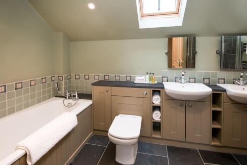 a bathroom with two sinks and a toilet and a bath tub at Time in Galashiels