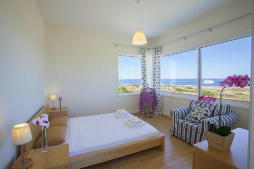 1 dormitorio con 1 cama, 1 silla y 1 ventana en Protaras Seafront Villa Melissa, en Protaras