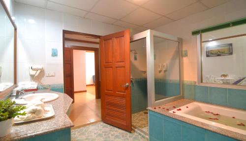 a bathroom with a tub and a sink and a shower at Chumphon Gardens Hotel in Chumphon