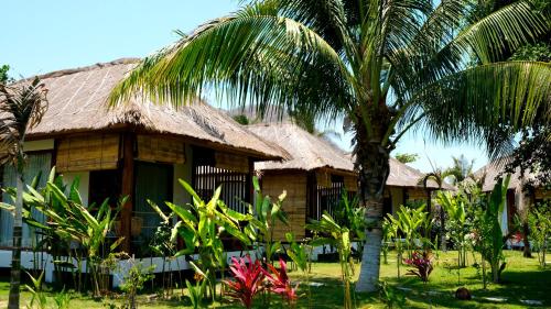 a house with a palm tree in front of it at Segara Lombok Beach Resort in Selong Belanak