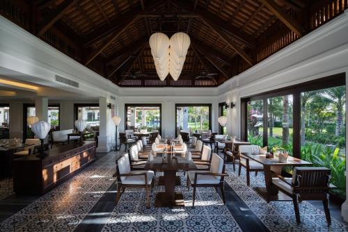 un restaurante con mesas, sillas y ventanas grandes en The Anam Cam Ranh en Cam Ranh