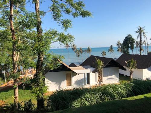 a white house with trees and the ocean in the background at Little Moon Villa in Ko Mak