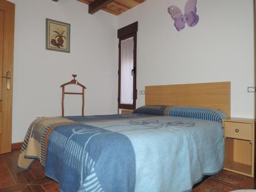Un dormitorio con una cama con una manta azul. en Los Aladros, en La Puebla de Valverde