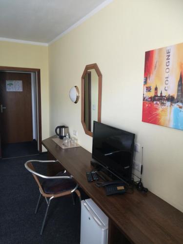 a room with a desk with a television and a mirror at Hotel Köln-Bonn in Bornheim