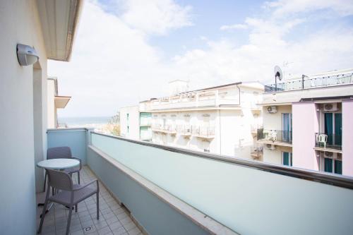 einen Balkon mit einem Tisch und einem Stuhl auf einem Gebäude in der Unterkunft Residence Marzia in Rimini