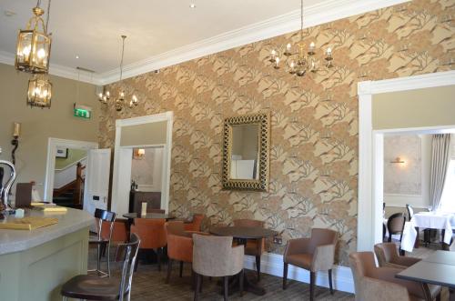 a restaurant with tables and chairs and a mirror on the wall at St Andrews Town Hotel in Droitwich