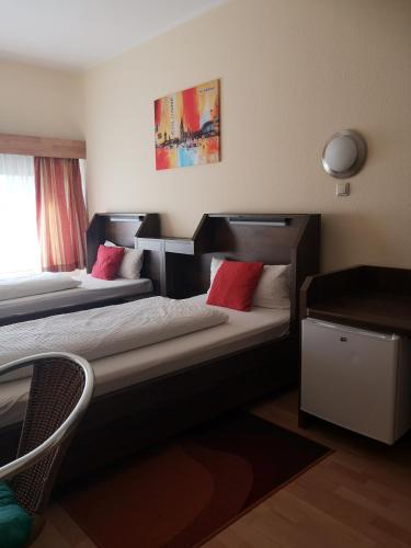 a bedroom with two beds with red pillows at Hotel Köln-Bonn in Bornheim