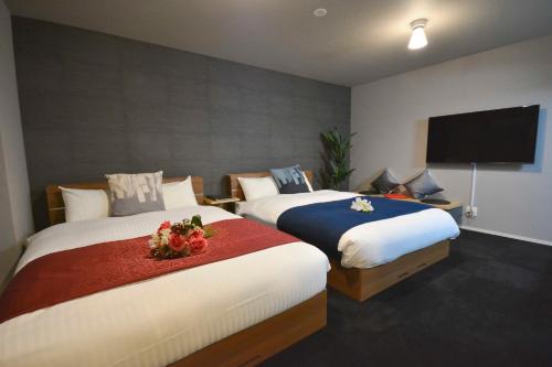 a bedroom with two beds and a flat screen tv at The Grand Residence Hotel Tenjin in Fukuoka