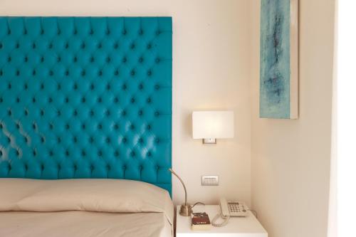 a bedroom with a blue headboard and a phone at Palazzo Montefusco in Sorrento