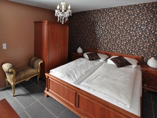 a bedroom with a large bed and a chair at Pension Schlossidyll in Wernigerode