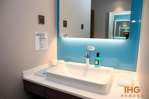 ein Badezimmer mit einem weißen Waschbecken und einem Spiegel in der Unterkunft Holiday Inn Express Litang, an IHG Hotel in Lithang