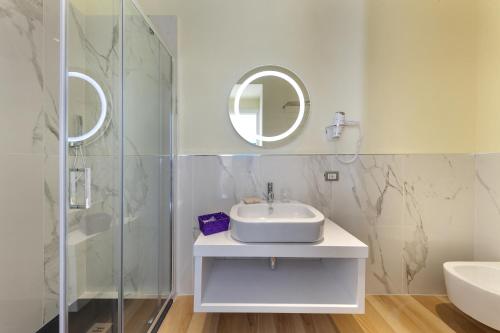 W białej łazience znajduje się umywalka i lustro. w obiekcie Palazzo Montefusco w Sorrento