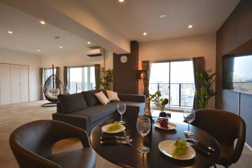 The Grand Residence Hotel Tenjin في فوكوكا: غرفة معيشة مع أريكة وطاولة وكراسي