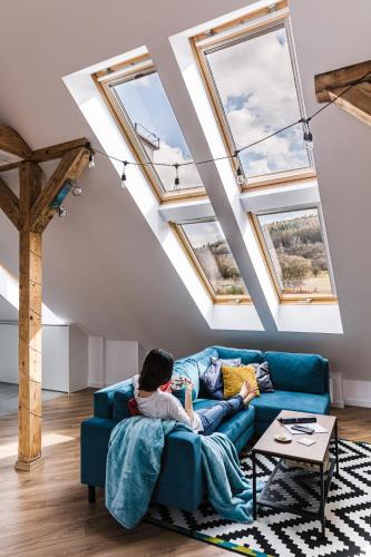 a man sitting on a blue couch in a room with windows at Apartament Dobre Miejsce 2 in Ustrzyki Dolne