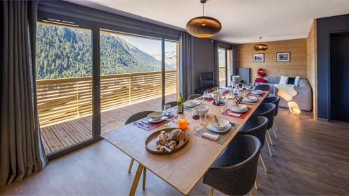 une grande table en bois avec des chaises et une grande fenêtre dans l'établissement The View - Apt 01 - BO Immobilier - Châtel - Châtel Multipass Vacances été 2025 en option au tarif de 3euros par jour et par personne, à Châtel