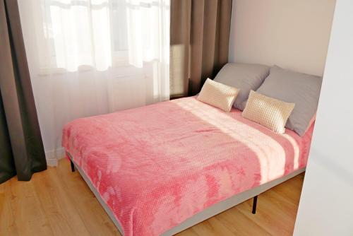 1 cama con manta rosa y 2 almohadas en Apartament 15, en Świnoujście