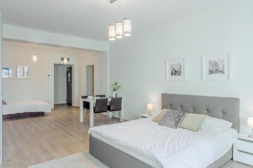 a white bedroom with a large bed and a dining room at ATLAS UNIRII: Upscale Flats in the Heart of Bucharest! in Bucharest