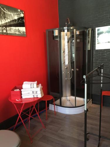 a shower in a room with a table and a red wall at La Maison Du Bulot in Fruges