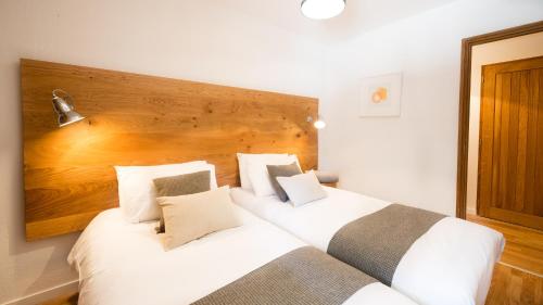 - une chambre avec 2 lits blancs et une tête de lit en bois dans l'établissement Les 4 Elements - Apt D102 - BO Immobilier, à Châtel