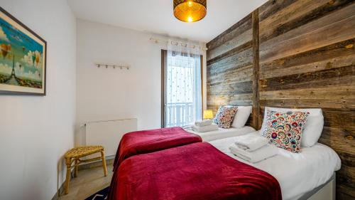 - une chambre avec un grand lit et un mur en bois dans l'établissement Les Freinets - Apt D102 - BO Immobilier - Châtel, à Châtel