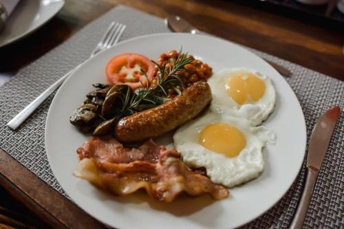 a plate of breakfast food with eggs sausage and tomatoes at Elegant Lodge & Conference Center in Pongola