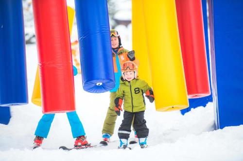 dos niños en esquís están parados en la nieve en Berg&Selig Apartment, en Pfarrwerfen