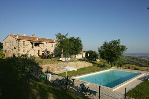 una casa y una piscina frente a una casa en Appartamento Melograno in casale con piscina - Val d'Orcia, en Radicofani