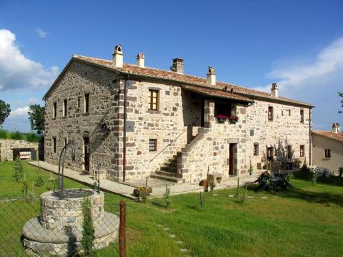 a large stone building with a grass yard in front of it at Appartamento Melograno in casale con piscina - Val d'Orcia in Radicofani