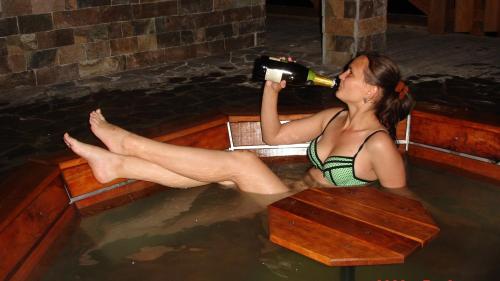 Eine Frau, die in einer Badewanne sitzt und eine Flasche Wein trinkt. in der Unterkunft Bilovoddya Hotel in Sil'