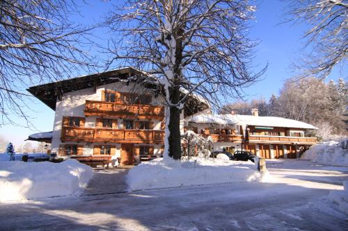 a large building in the snow with a tree at Kapler Alm in Waakirchen