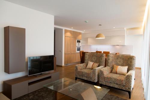 a living room with two chairs and a television at Apartamentos Turisticos da Nazare in Nazaré