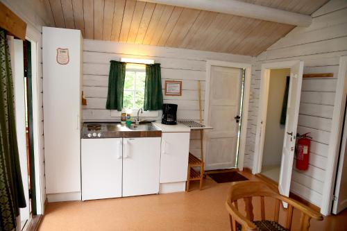 Elle comprend une petite cuisine avec des placards blancs et une fenêtre. dans l'établissement FOSSEN CAMPING, à Geiranger