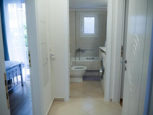 biała łazienka z toaletą i umywalką w obiekcie Garden Apartment next to the Mall -Private Parking w Atenach