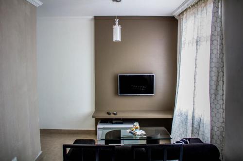 a living room with a table and a tv on a wall at MonteSanto Del Rey in Belo Horizonte