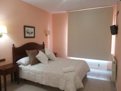 a bedroom with a bed and a large window at Hostal Restaurante Pacos in Herrera del Duque